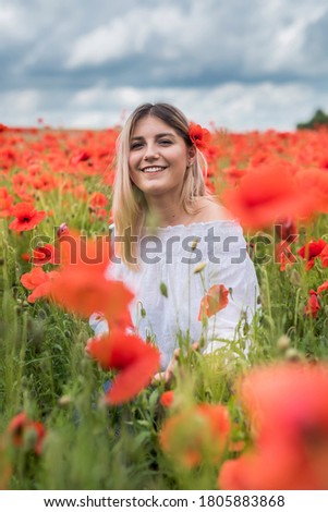 Young woman is standing near blooming poppy field . happy woman at outdoor, lifestyle