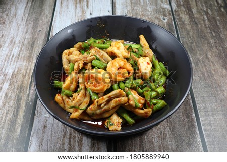 Traditional fried and stirred cutting green bean with chopped chicken thigh and fresh peeled shrimp seasoning with red chilly paste on the plate. Famous Thai hot and spicy food in Asia restaurant.  Royalty-Free Stock Photo #1805889940