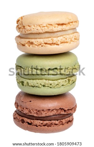 Pastries, desserts and sweets. Close-up of a yellow french vanilla macaroon, a green pistachio macaroon and a brown chocolate macaroon isolated on a white background. Macro photograph.