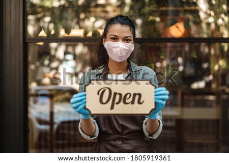 Woman coffee shop owner with face mask opens after lockdown quarantine