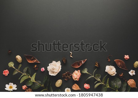 Autumnal-winter concept with dried flowers, branches of eucalyptus, leaves and berries on dark background. Frame of plants. Flat lay, copy space.