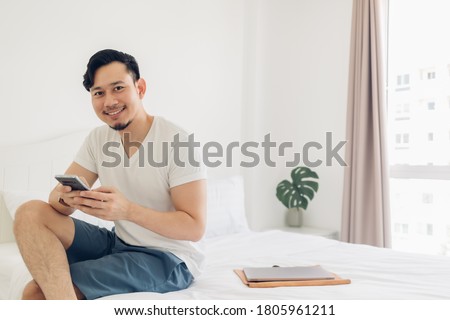 Asian man is using the smartphone on his bed in concept of relaxation.