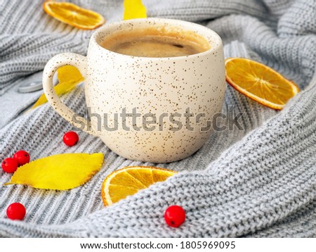 Autumn, fall leaves, hot steaming cup of coffee and a cozy grey sweater on wooden rustic background. Seasonal, morning coffee, Sunday relaxing and still life concept. Square photo size. Front view