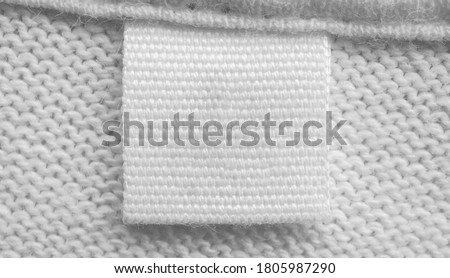 White blank laundry care clothes label on cotton shirt background