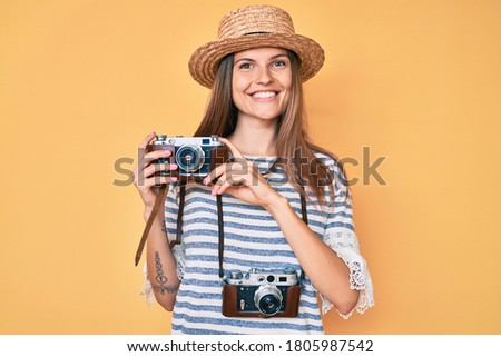 Beautiful caucasian tourist woman holding vintage camera smiling with a happy and cool smile on face. showing teeth. 