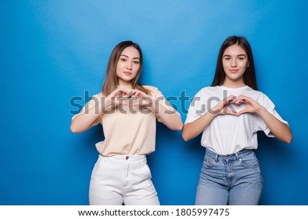 Two mixed race woman make heart on blue background