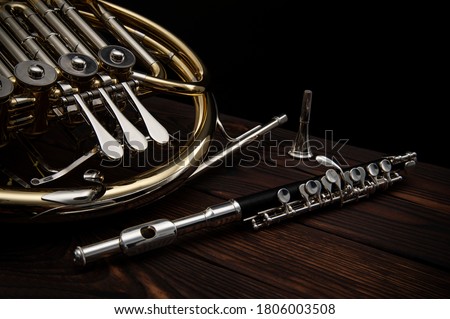 Two musical instruments French horn and flute on a wooden surface on a black background Royalty-Free Stock Photo #1806003508