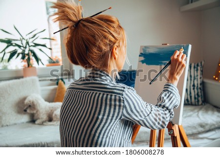 Beautiful artist woman painting in her room.