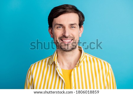 Portrait of satisfied attractive man look good mood in camera toothy smiling wear striped yellow shirt isolated over blue color background