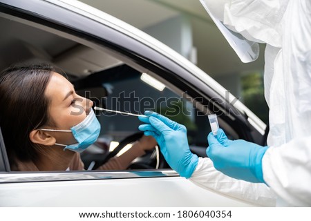Portrait of asian woman drive thru coronavirus covid-19 test by medical staff with PPE suit by nose swab. New normal healthcare drive thru service and medical concept. Royalty-Free Stock Photo #1806040354