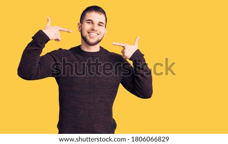 Young handsome man wearing casual sweater smiling cheerful showing and pointing with fingers teeth and mouth. dental health concept. 