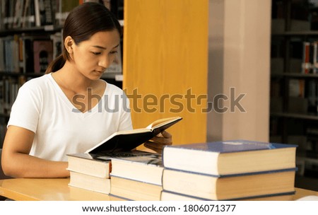 Young Asian woman college students research and learn from textbooks  