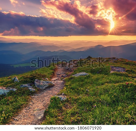 Amazing mountain landscape with colorful vivid sunset on the cloudy sky and path through the rocks, natural outdoor travel background. Beauty world. Royalty-Free Stock Photo #1806071920