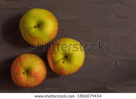 View from above on three fresh apples that lie on a dark gray background
