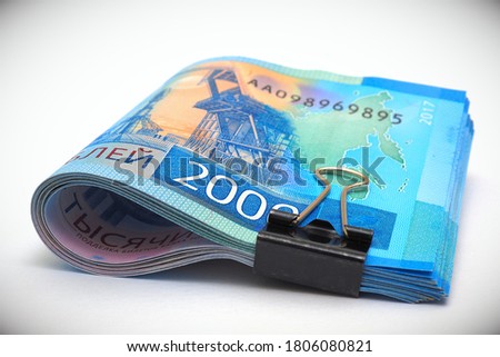 A rolled up bundle of Russian bills of 2000 rubles. Money tied with an office clip and lie on a white background with vignetting. Child support allowance and unemployment benefit in Russia. Macro