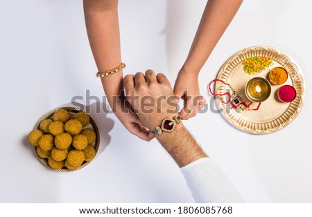 Close up top view of female hands tying colorful rakhi on her brother’s hand isolated on white background on Raksha Bandhan Festival Royalty-Free Stock Photo #1806085768