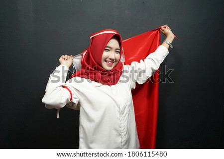 Portrait of young Asian female wearing red and white Indonesian flag attribute. Independence day concept.