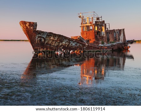 last sun lights on the board of ship wreck on shallow at sea in summer day