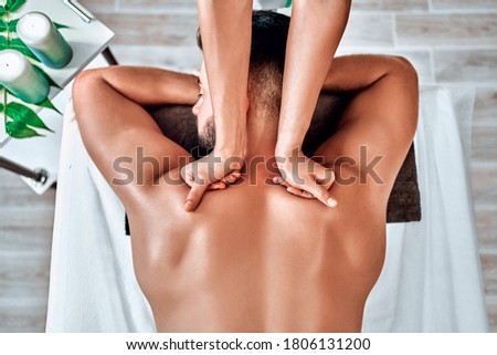 Handsome man relaxing and enjoying a deep tissue back massage at the spa salon. Top view Royalty-Free Stock Photo #1806131200