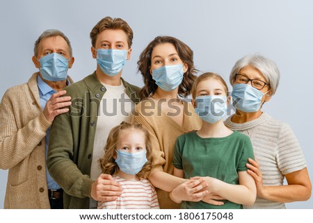 Family is wearing facemasks during coronavirus and flu outbreak. Virus and illness protection, quarantine. COVID-2019. Taking on or taking off masks. People on white wall background. Royalty-Free Stock Photo #1806175048