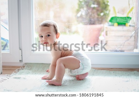 Cute baby boy in diaper crawling next to window home. Mixed race Asian-German infant first step crawl. Happy kid learn and play. Royalty-Free Stock Photo #1806191845