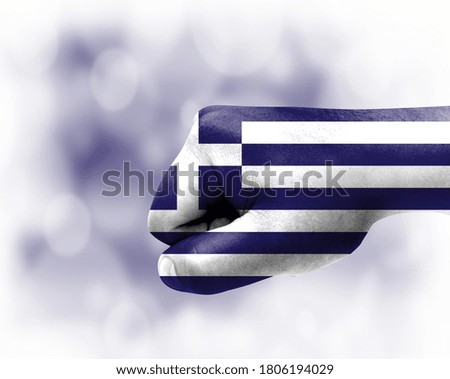 Flag of Greece painted on male fist, strength,power,concept of conflict. On a blurred background.
