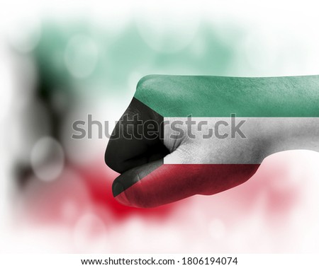 Flag of Kuwait painted on male fist, strength,power,concept of conflict. On a blurred background.