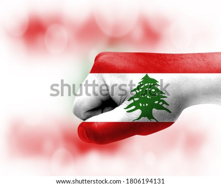 Flag of Lebanon painted on male fist, strength,power,concept of conflict. On a blurred background.