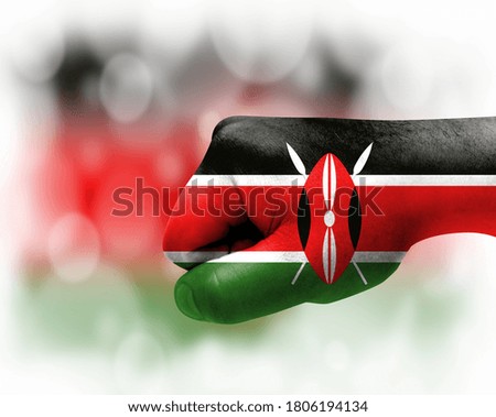 Flag of Kenya painted on male fist, strength,power,concept of conflict. On a blurred background.