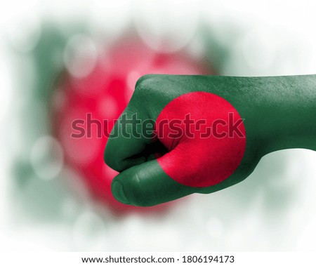 Flag of Bangladesh painted on male fist, strength,power,concept of conflict. On a blurred background.