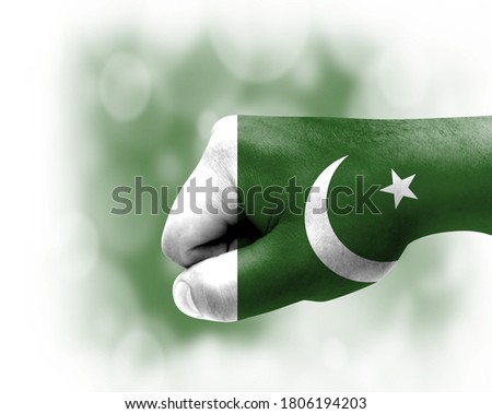 Flag of Pakistan painted on male fist, strength,power,concept of conflict. On a blurred background.