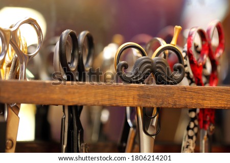 Mustache shaped hair clip on a barber scissors stand and empty space for text