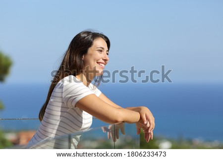 Happy woman contemplating seascape in a hotel balcony on the beach Royalty-Free Stock Photo #1806233473