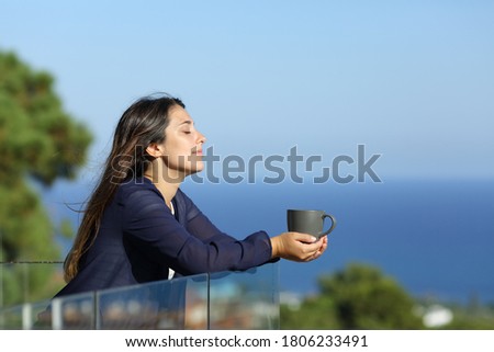 Profile of a relaxed woman in a hotel balcony with a cofee cup on the beach on summer vacation Royalty-Free Stock Photo #1806233491