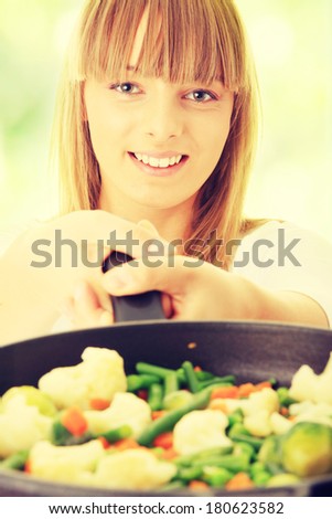 Image of a young woman cooking healthy food,against abstract green background