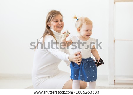 Young mother playing with her baby girl at home. Motherhood, infant and children concept.