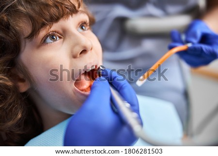 Close-up photo of a child opening mouth widely while dentist use dental drill for medical treatment