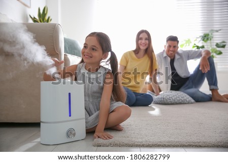 Family in room with modern air humidifier Royalty-Free Stock Photo #1806282799