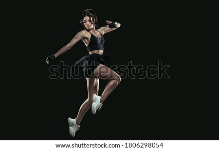 Beautiful young female athlete practicing on black background