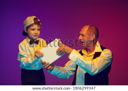 Senior man and little boy on gradient background, copyspace