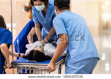 Medical team do CPR Cardiopulmonary resuscitation to seriously injured patient with oxygen mask while push gurney stretcher bed to Operating Room. Emergency health care and medical hospital concept. Royalty-Free Stock Photo #1806329530
