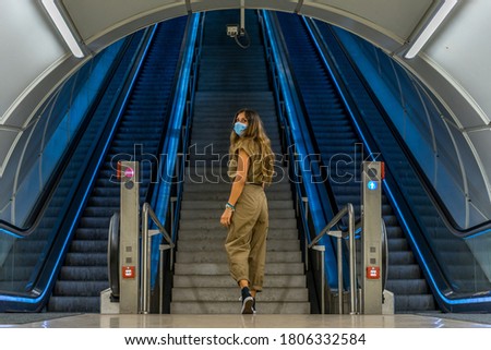 woman walking through a subway station with her surgical mask Royalty-Free Stock Photo #1806332584