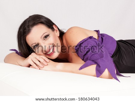 Anne Hathaway look alike lying on an ottoman with a beautiful big smile. Royalty-Free Stock Photo #180634043