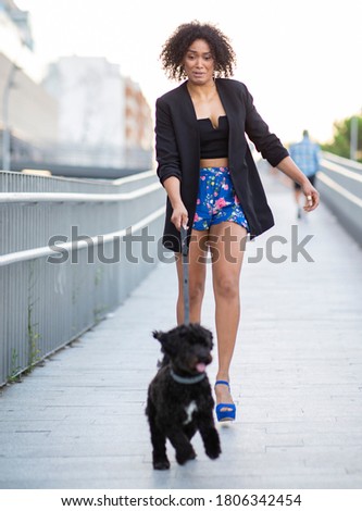pretty African American woman with a dog walking in the city