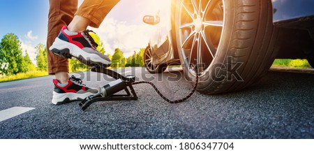 Driver using a foot pump to inflate a tire Royalty-Free Stock Photo #1806347704