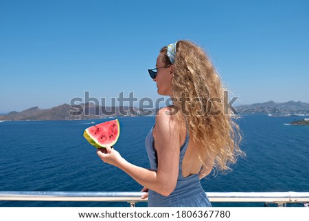beautiful woman with a slice of watermelon wearing swimsuit looking at sea view holiday summer