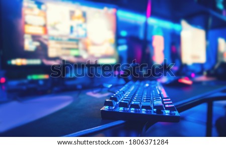 Professional computer mouse for video games and cyber sports on background of monitor, neon color.