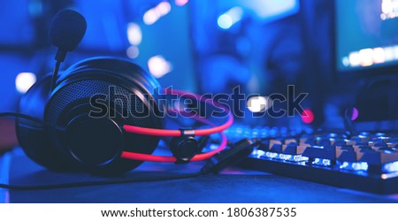 Headphones for professional esports streamer against background of computer and gaming keyboard.