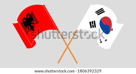Crossed and waving flags of Albania and South Korea