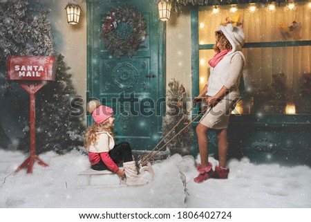 mom walks with her daughter on a sled on Christmas night near the house